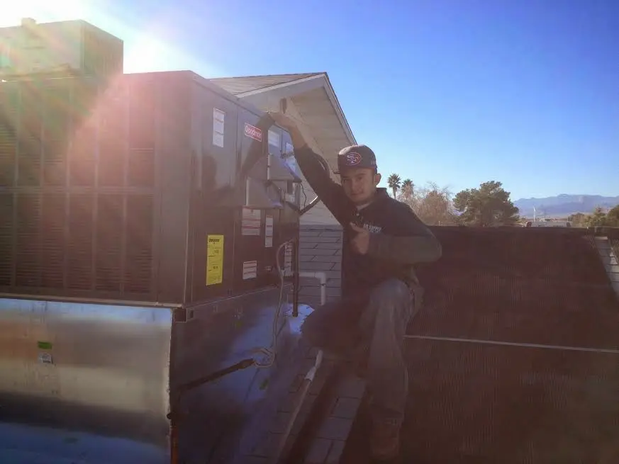 HVAC technician performing AC Tune-Up on a rooftop unit in Hutchison