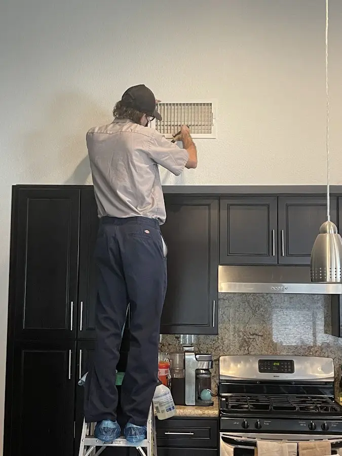 Technician inspecting an air vent during HVAC service in Hutchison